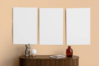 Odadaki bej duvarın yanındaki çekmecelerin üstündeki boş posterler ve dekorlar. Yakın çekim.