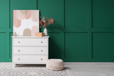 Dekorlu çekmeceler ve oda yeşil duvarın yanında puf.