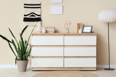 Dekorlu, çiçekli ve lambalı çekmeceler. Odadaki bej duvarın yanında.