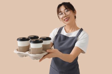 Bej arka planda kahve fincanı olan bayan barista.