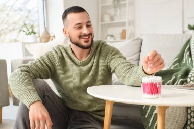 Evde pamuklu tomurcukları olan genç bir adam.