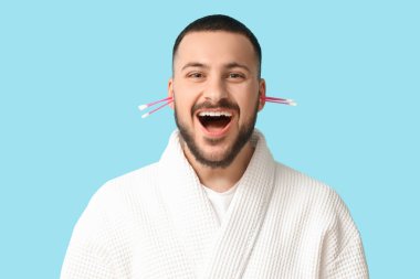 Mavi arka planda pamuk tomurcukları olan genç bir adam