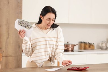 Mutfaktaki masada parası ve para iadesi olan genç bir kadın.