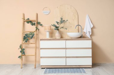 Banyo içinde merdiven ve bej duvarın yanında çekmeceler var.