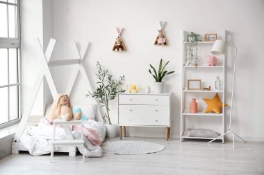 Beyaz duvarın yanında raflar, yatak ve çekmeceler olan çocuk odasının içinde.