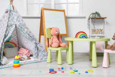 Çocuk odasının içinde masa, çadır ve oyuncaklar var.