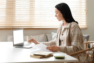 Masada dizüstü bilgisayar kullanan, para iadesi formu olan genç bir kadın.
