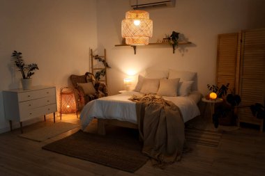 Yatak odasının içinde bej ekose kumaşlar, çekmeceler ve geceleri parlayan lambalar.