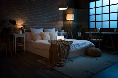 Yatak odasının içinde dizüstü bilgisayar ve geceleri parlayan lambalar.