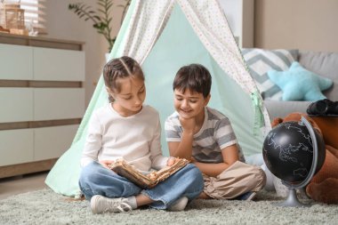 Evde macera kitabı okuyan sevimli çocuklar.