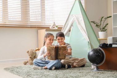 Evde macera kitabı okuyan sevimli çocuklar.