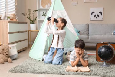 Evde dürbünlü şirin çocuklar macera kitabı okuyor.