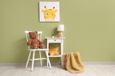 Çocuk odasının içinde sandalye, masa ve resim var.