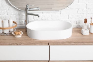 Lavabo ve banyo malzemeleriyle dolu sandık şık bir banyoda beyaz tuğla duvarın yanında.