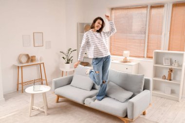 Evdeki kanepede dans eden genç kadın.