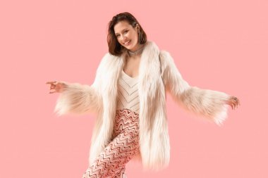 Pembe arka planda dans eden kürklü genç bir kadın.