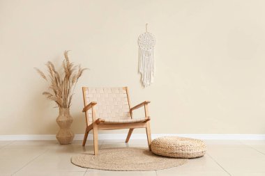 Sandalye, puf ve pampa vazoda bej duvarın yanındaki vazoda.