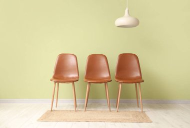 Kahverengi sandalyeler ve asılı lamba yeşil duvarın yanında