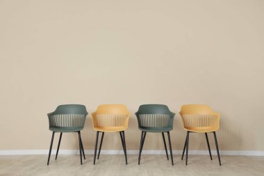 Bej duvarın yanında sarı ve yeşil sandalyeler.