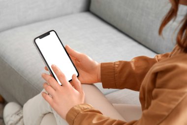 Evde boş cep telefonu kullanan genç bir kadın, yakın plan.