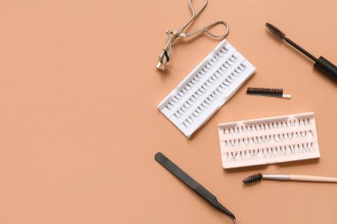 Bej arka planda farklı takma kirpik, fırça, cımbız ve bigudi seti