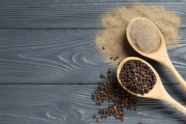 Siyah biber tozlu kaşıklar ve koyu ahşap arka planda karabiber.