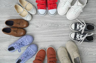 Gri ahşap arka planda farklı çocuk ayakkabılarından yapılmış çerçeve