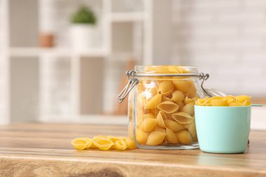 Mutfaktaki masada çiğ makarna kabuğu ve ölçü kabıyla dolu kavanoz.