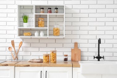 Mutfaktaki masada çiğ makarna kabuğu olan kavanozlar ve kâse.