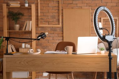 Ofisinde dizüstü bilgisayarı ve mikrofonu olan blog yazarının çalışma yeri