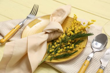 Sarı ahşap arka planda mimoza çiçekleri olan güzel bir masa, yakın plan.