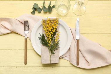 Mimoza çiçekleri ve sarı ahşap arka planda okaliptüs olan güzel bir masa.