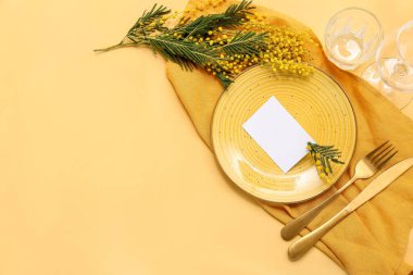 Boş bir kart ve sarı arka planda mimoza çiçekleri olan güzel bir masa.