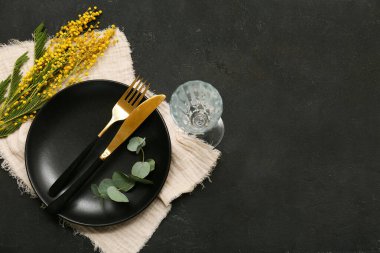 Siyah zemin üzerinde mimoza çiçekleri ve okaliptüs olan güzel bir masa.