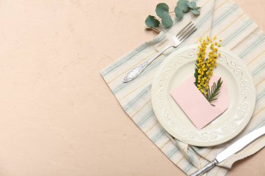Zarfla ve bej arkaplanlı mimoza çiçekleriyle güzel bir masa.