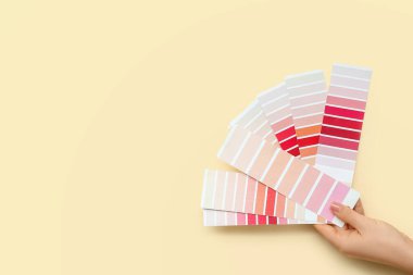 Sarı arka planda farklı renk paletleri olan kadın el.