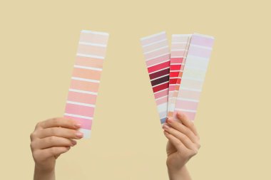 Sarı arka planda farklı boya paletleri olan kadın elleri, yakın plan