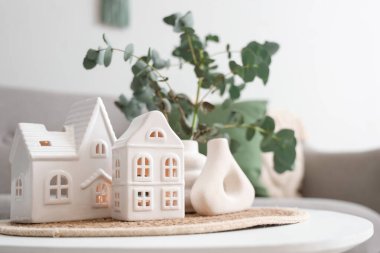 Hasır paspas, ev mumu tutacakları ve yeşil dallı vazolar oturma odasında, yakın plan.