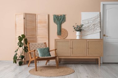 Koridorun içinde koltuk, çekmeceler ve bej duvarın yanında katlanır ekran var.