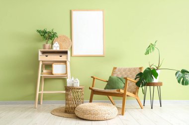 Oturma odasının içinde, yeşil duvarın yanındaki ev şeklinde koltuk, masa ve mum tutacakları var.