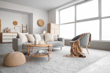 Masanın üzerinde ev şeklinde mum tutacakları olan aydınlık oturma odasının içinde.