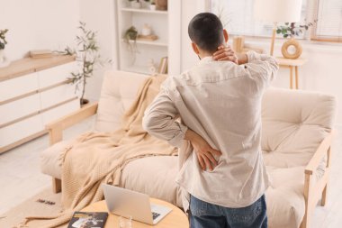 Evde sırt ağrısı çeken genç bir adam.
