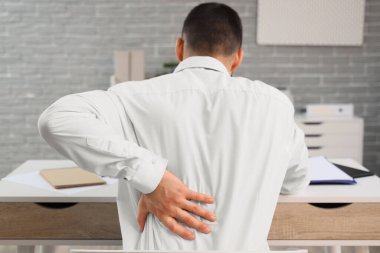 Ofiste sırt ağrısı çeken genç bir işadamı.