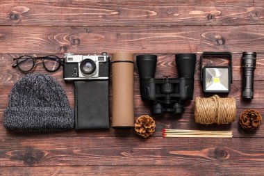 Ahşap arka planda farklı seyahat öğeleri, şapka, defter ve termosa sahip kompozisyon