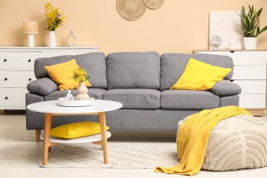 Kanepe, puf ve vazolarda mimoza çiçekleri olan oturma odasının içinde.