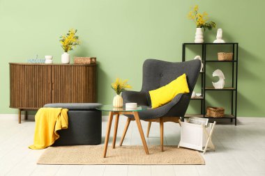 Oturma odasının içinde vazolarda koltuk ve mimoza çiçekleri var.