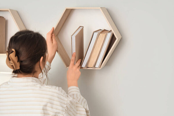Женщина кладет книгу на полку в гостиной. Крупный план