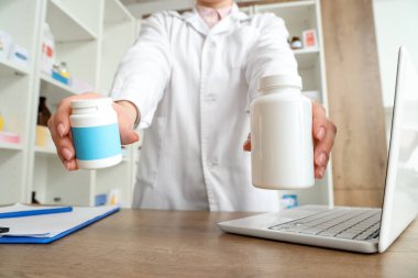 Eczanede ilaç şişeleri olan kadın eczacı, yakın plan.