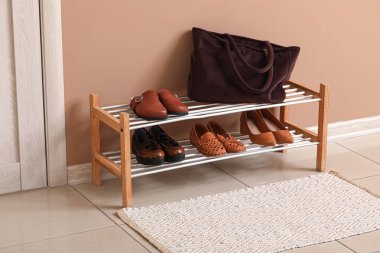 Modern koridorun içindeki kahverengi duvarın yanındaki ayakkabılar için ayağa kalkın.