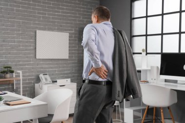 Ofiste sırt ağrısı çeken olgun bir iş adamı.